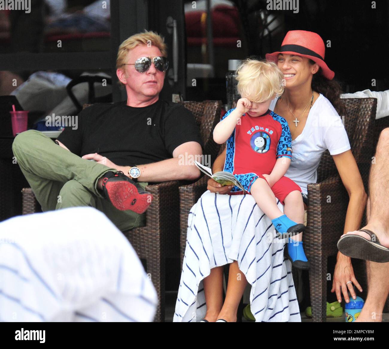 Boris Becker e sua moglie Lily sono stati visti godendo mojitos mentre si rilassavano in piscina con gli amici in un hotel a South Beach. Dopo aver trascorso diversi giorni sotto il sole di Miami, Boris sembrava un po' rosso sul viso, segni di una possibile scottatura del sole. Lily indossava un cappello color salmone con una parte superiore bianca e pantaloncini con motivi floreali sopra il bikini. Il figlio adorabile Amadeus di 2 anni è stato visto giocare in piscina mentre la mamma lo guardava. Ad un certo punto Lily ha letto un libro ad Amadeus mentre si è seduto sul suo grembo. Miami, Florida. 6th aprile 2012. . Foto Stock