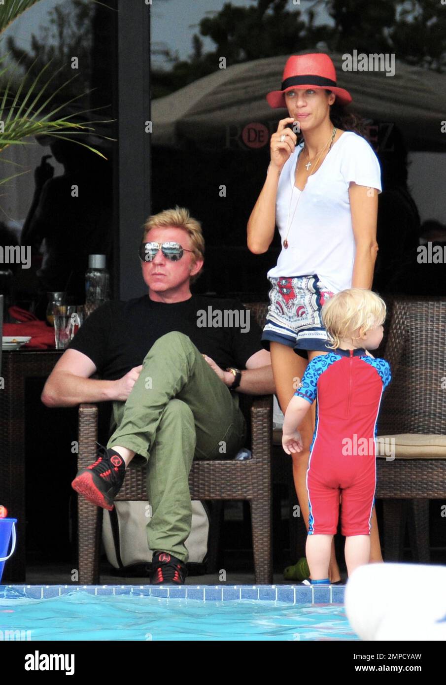 Boris Becker e sua moglie Lily sono stati visti godendo mojitos mentre si rilassavano in piscina con gli amici in un hotel a South Beach. Dopo aver trascorso diversi giorni sotto il sole di Miami, Boris sembrava un po' rosso sul viso, segni di una possibile scottatura del sole. Lily indossava un cappello color salmone con una parte superiore bianca e pantaloncini con motivi floreali sopra il bikini. Il figlio adorabile Amadeus di 2 anni è stato visto giocare in piscina mentre la mamma lo guardava. Ad un certo punto Lily ha letto un libro ad Amadeus mentre si è seduto sul suo grembo. Miami, Florida. 6th aprile 2012. . Foto Stock