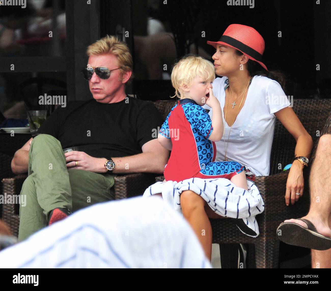 Boris Becker e sua moglie Lily sono stati visti godendo mojitos mentre si rilassavano in piscina con gli amici in un hotel a South Beach. Dopo aver trascorso diversi giorni sotto il sole di Miami, Boris sembrava un po' rosso sul viso, segni di una possibile scottatura del sole. Lily indossava un cappello color salmone con una parte superiore bianca e pantaloncini con motivi floreali sopra il bikini. Il figlio adorabile Amadeus di 2 anni è stato visto giocare in piscina mentre la mamma lo guardava. Ad un certo punto Lily ha letto un libro ad Amadeus mentre si è seduto sul suo grembo. Miami, Florida. 6th aprile 2012. . Foto Stock