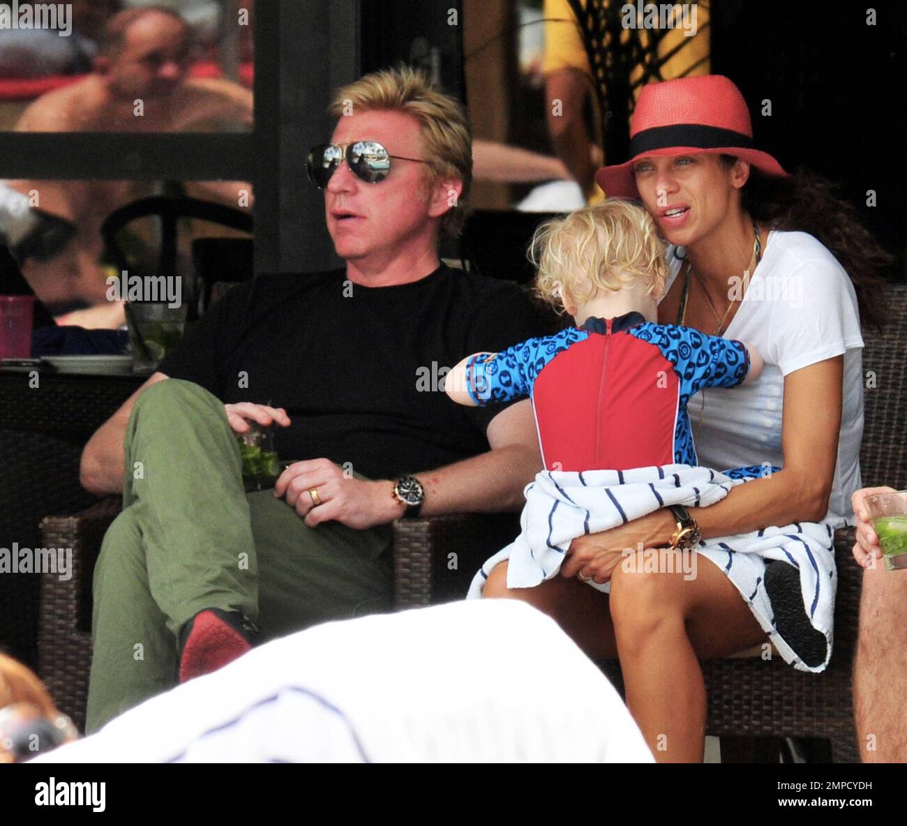 Boris Becker e sua moglie Lily sono stati visti godendo mojitos mentre si rilassavano in piscina con gli amici in un hotel a South Beach. Dopo aver trascorso diversi giorni sotto il sole di Miami, Boris sembrava un po' rosso sul viso, segni di una possibile scottatura del sole. Lily indossava un cappello color salmone con una parte superiore bianca e pantaloncini con motivi floreali sopra il bikini. Il figlio adorabile Amadeus di 2 anni è stato visto giocare in piscina mentre la mamma lo guardava. Ad un certo punto Lily ha letto un libro ad Amadeus mentre si è seduto sul suo grembo. Miami, Florida. 6th aprile 2012. . Foto Stock