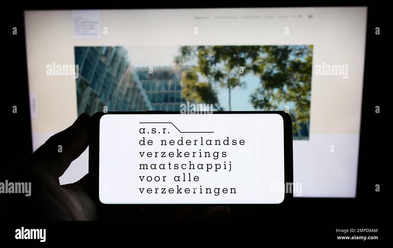 Persona che detiene uno smartphone con il logo della compagnia di assicurazione olandese ASR Nederland N.V. sullo schermo di fronte al sito Web. Messa a fuoco sul display del telefono. Foto Stock