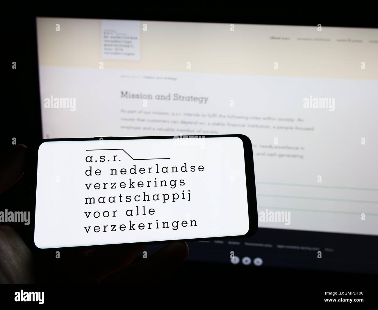 Persona che tiene il cellulare con il logo della compagnia di assicurazione olandese ASR Nederland NV sullo schermo di fronte alla pagina web aziendale. Messa a fuoco sul display del telefono. Foto Stock