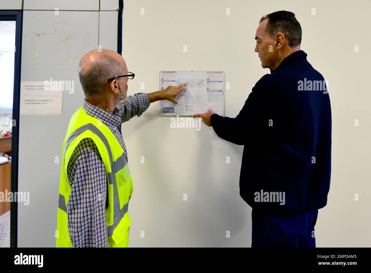 A sinistra, Marco Ruberti, Safety Specialist, assegnato al Battaglione di supporto dell'Esercito – Africa, 405th Brigata di supporto dell'Esercito – Europa e Africa, mostra Luciano Lazzeri, ispettore antincendio, assegnato ai servizi di emergenza dei Vigili del fuoco, Camp Darby USAG Italia, la mappa dell'edificio e il piano di evacuazione in caso di incendio, durante la settimana di prevenzione degli incendi. Camp Darby, DEPOT, Italia, 13 ottobre 2022. Foto Stock