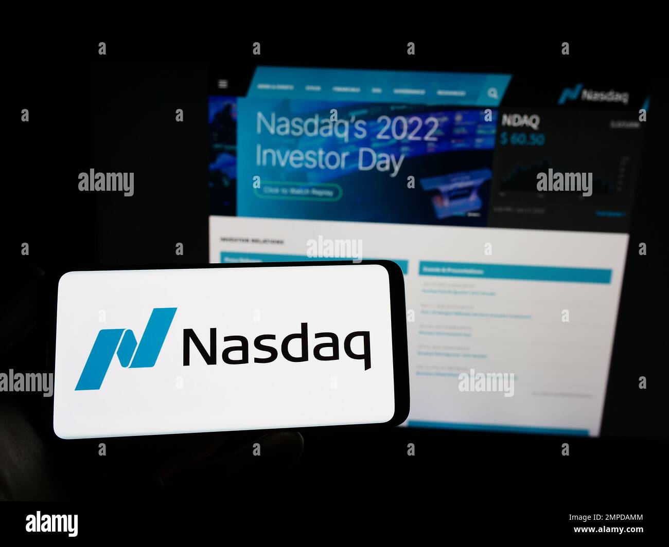 Persona in possesso di smartphone con il logo della borsa valori statunitense Nasdaq sullo schermo di fronte al sito Web. Messa a fuoco sul display del telefono. Foto Stock