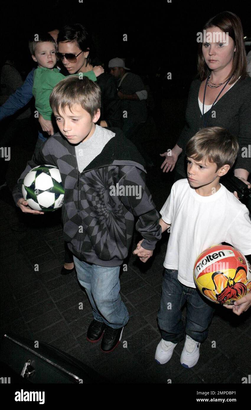 Victoria Beckham e i suoi tre figli Brooklyn, Romeo e Cruz arrivano all'aeroporto internazionale di Los Angeles dopo un volo da Londra. La famiglia è stata circondata da guardie del corpo e personale che li ha guidati attraverso la folla fino al loro veicolo in attesa. Brooklyn e Romeo camminarono mano in mano, ognuno portava la propria palla da calcio, mentre Victoria trasportava la piccola Cruz che sembrava stanca dal viaggio. Los Angeles, California. 4/10/09. F Foto Stock