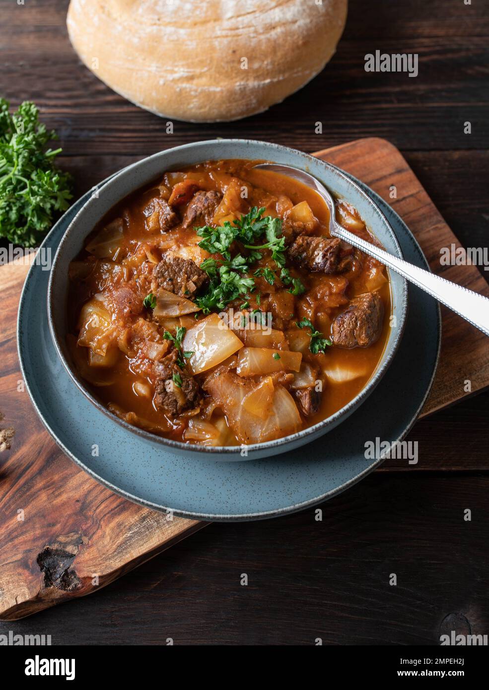 Stufato di manzo con cavolo e verdure. Servita su sfondo rustico e in legno con pane di ciabatta fatto in casa. Vista dall'alto Foto Stock