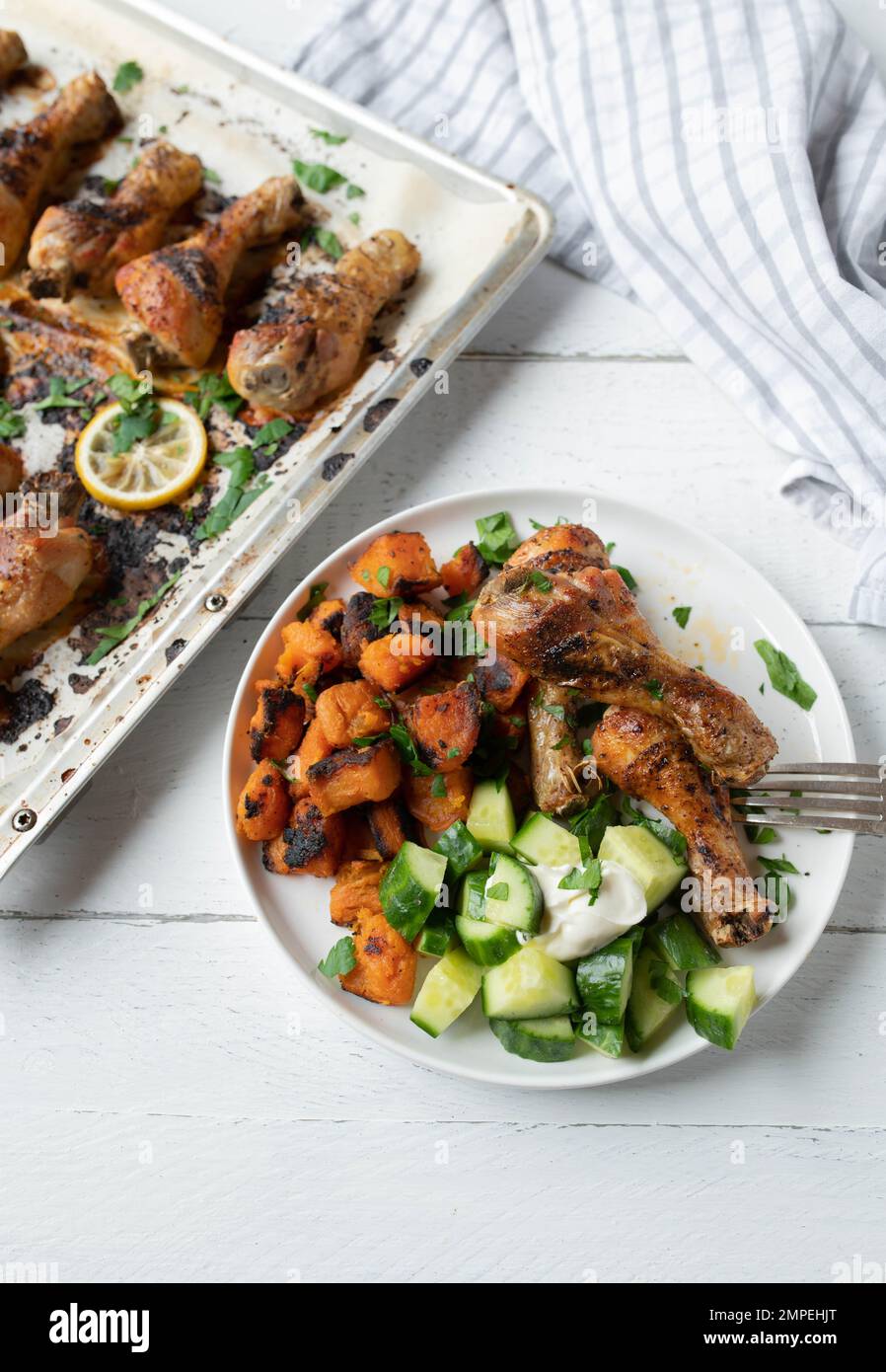 Cena leggera o pranzo con bastoncini di pollo al forno, patate dolci arrostite e insalata di cetrioli Foto Stock