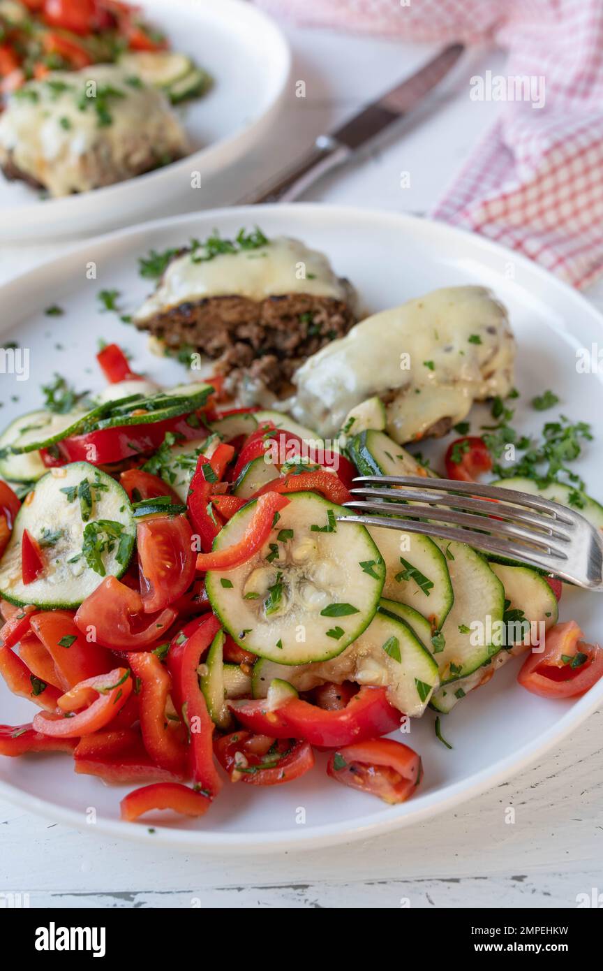 Cena o pranzo a basso contenuto di carboidrati con insalata mediterranea fresca e polpette o hamburger su piatto Foto Stock