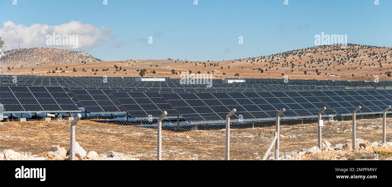 Campo solare con pannelli solari recintati al tramonto Foto Stock