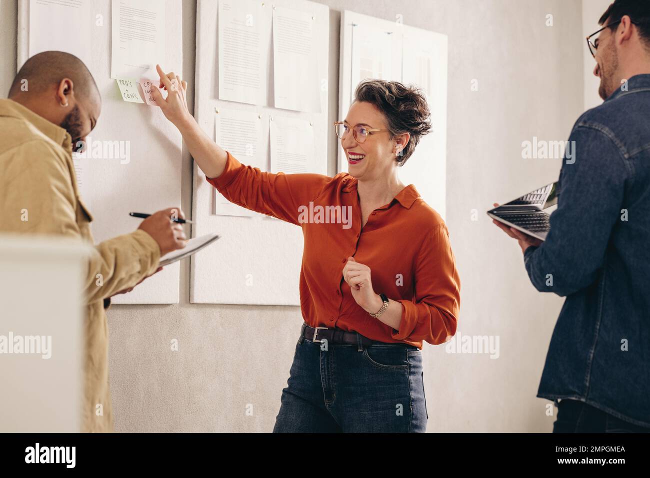 Allegra donna d'affari che ride felicemente mentre ha una discussione con il suo team. Gruppo di diversi imprenditori che lavorano su una nuova strategia di marketing i Foto Stock