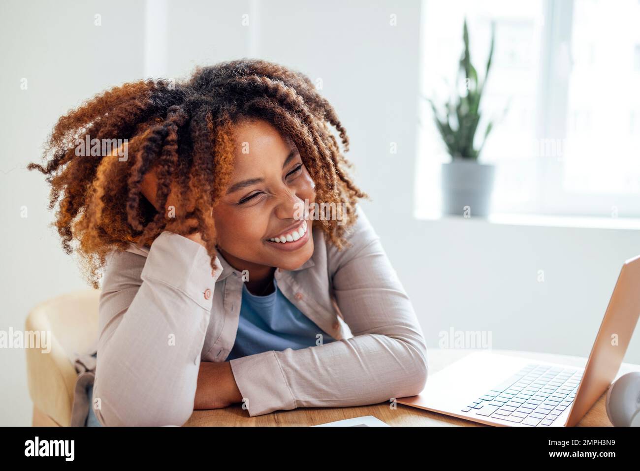 Una giovane afroamericana sta lavorando su un computer portatile. Una studentessa focalizzata sta guardando lo schermo del computer e guardando il webinar o facendo videochat Foto Stock
