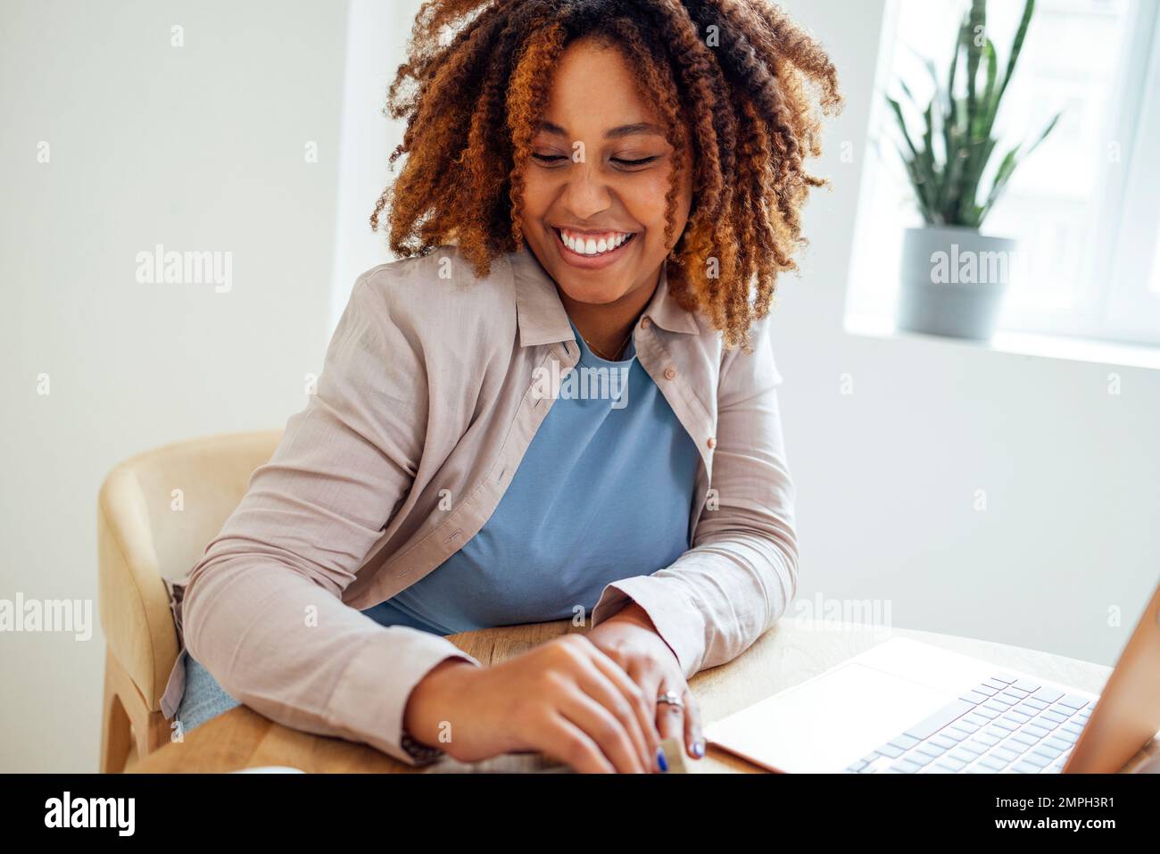 Una giovane afroamericana sta lavorando su un computer portatile. Una studentessa focalizzata sta guardando lo schermo del computer e guardando il webinar o facendo videochat Foto Stock