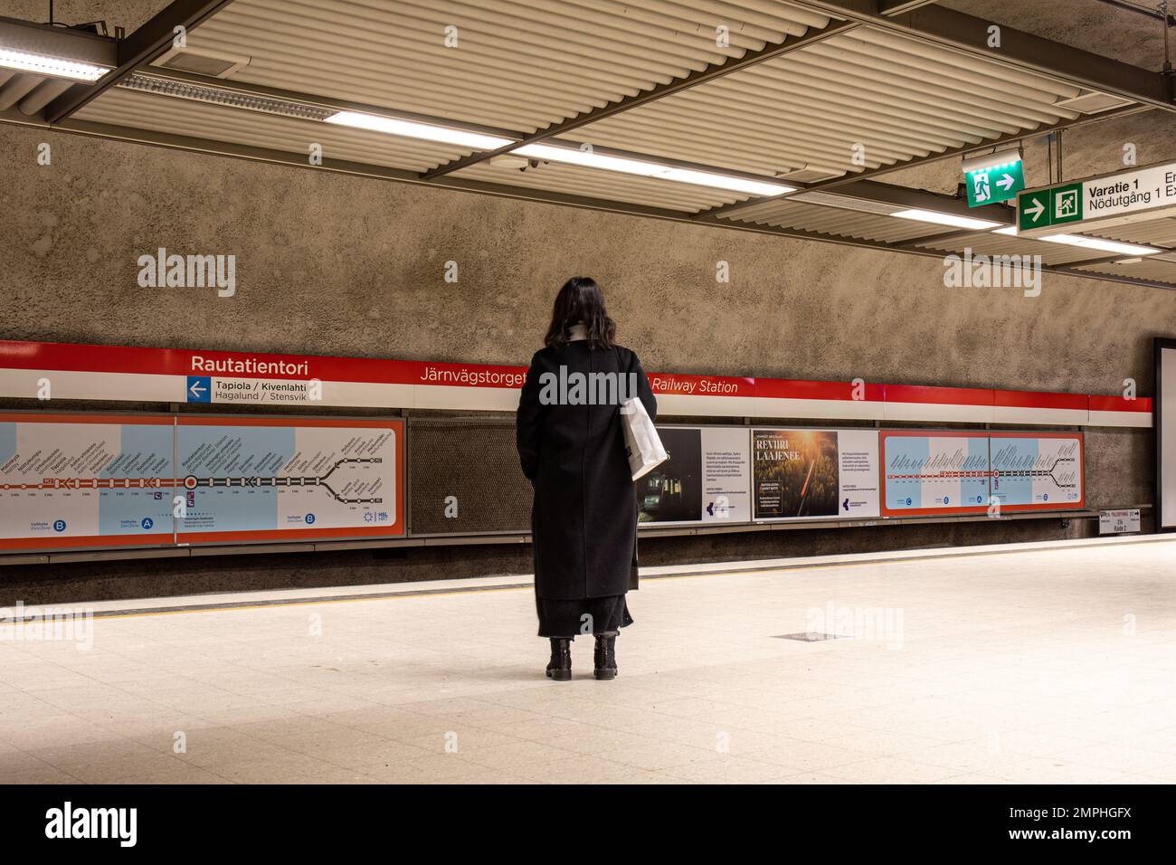 Donna in attesa di un treno alla stazione della metropolitana Rautatientori a Helsinki, Finlandia Foto Stock