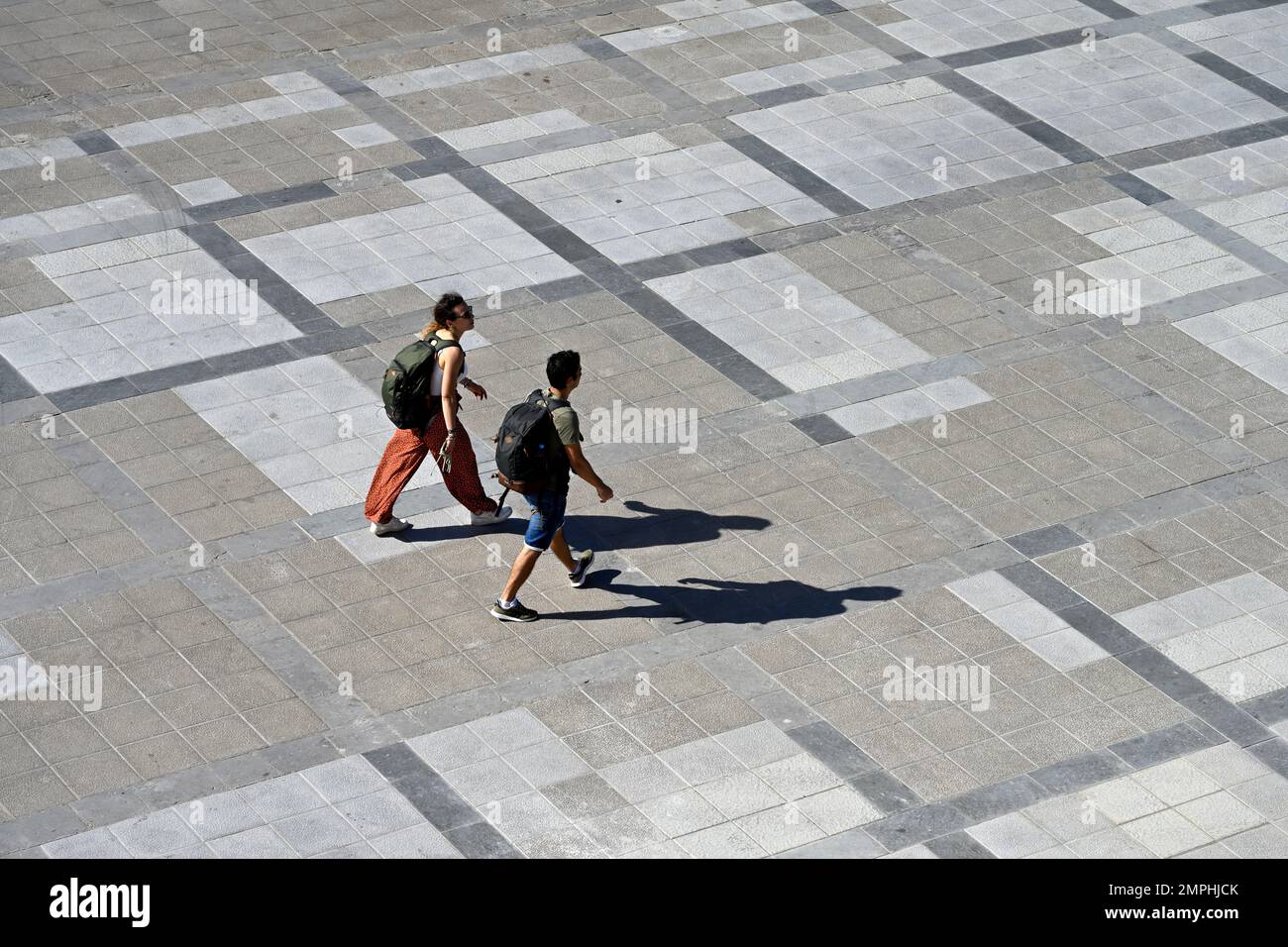 Vista dall'alto di due persone che camminano nella piazza pubblica con ombre Foto Stock