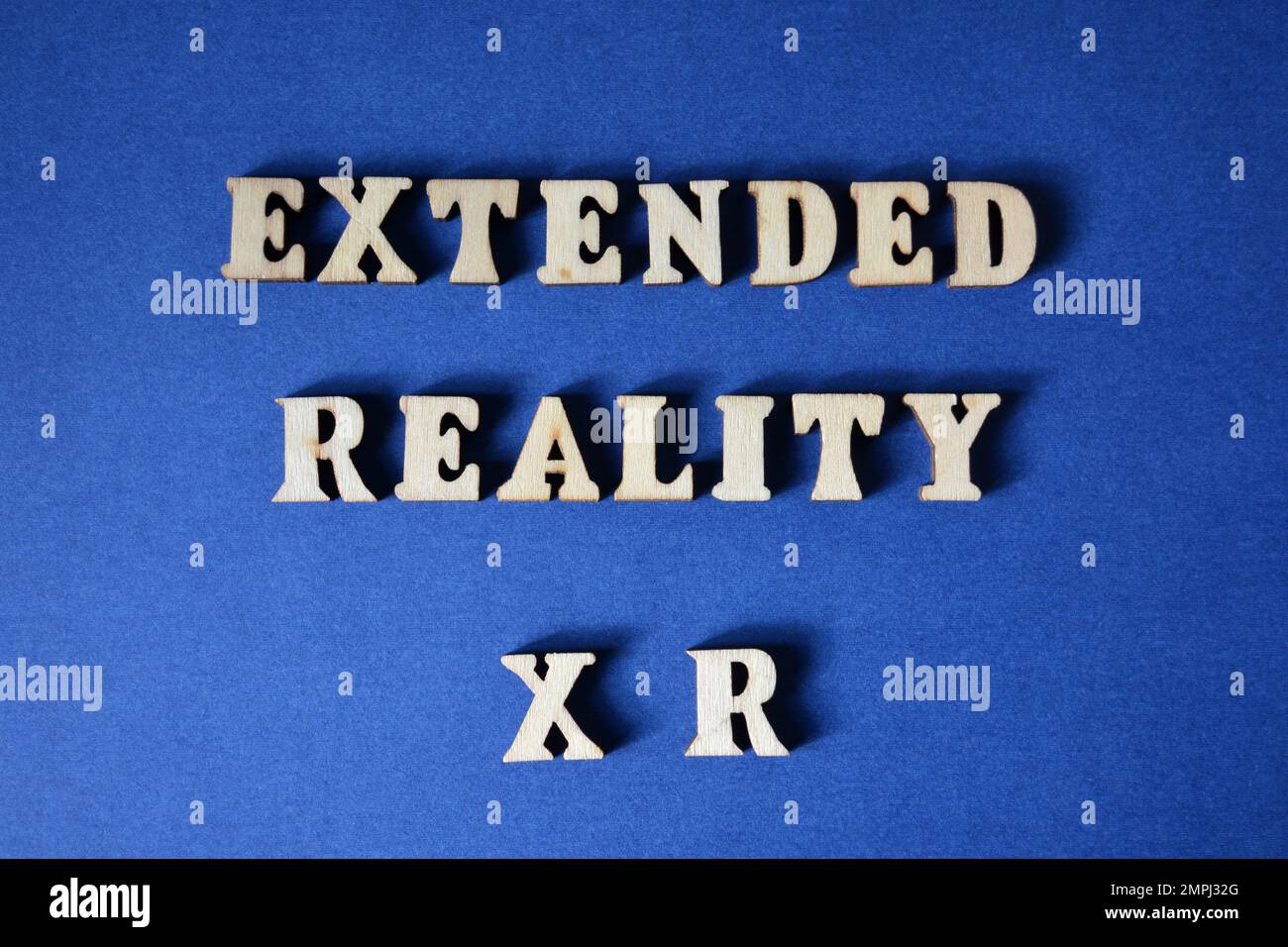 Extended Reality XR, parole in lettere alfabetiche di legno isolate su sfondo blu Foto Stock