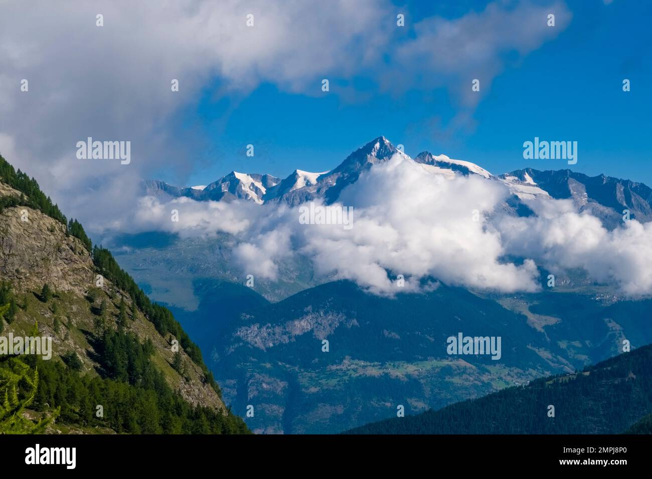 Scenario alpino di cime parzialmente innevate, che si ergono dalle nuvole, che si elevano sulla valle del Rodano. Foto Stock