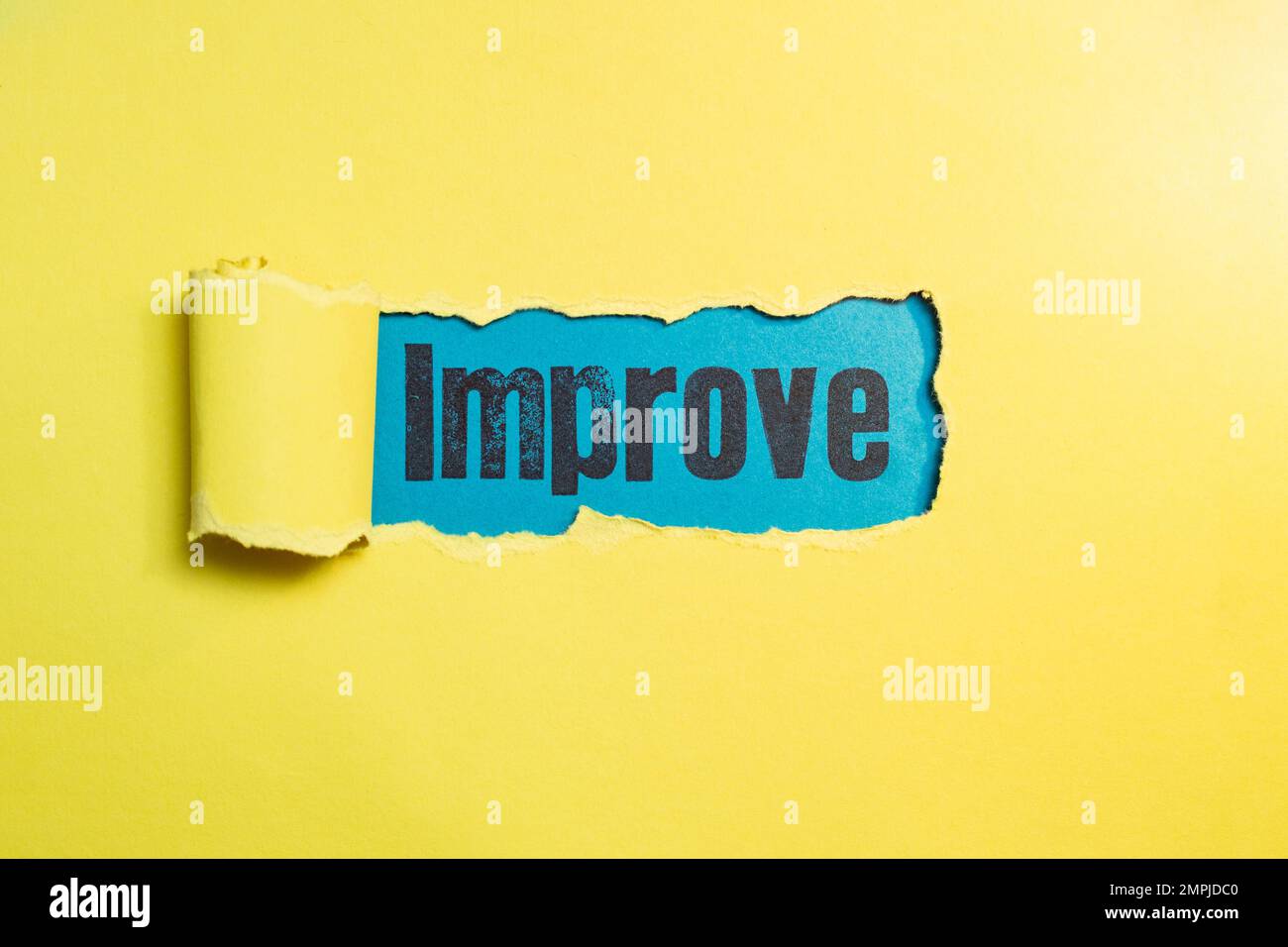 Migliorare la scrittura con lettere di timbro sulla grana della carta blu attraverso una striscia strappata su carta gialla. Foto Stock