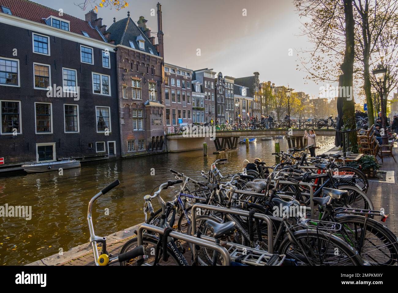 Biciclette parcheggiate sul bordo del canale Voorburgwal Oudezijds con il ponte di strada Armbrug sullo sfondo. Foto Stock