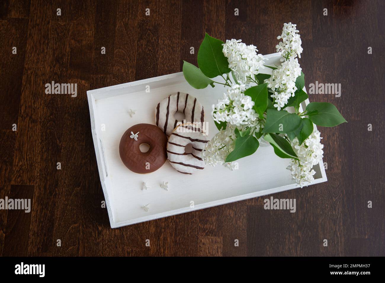 ciambelle e fiori di lilla bianca sul vassoio Foto Stock