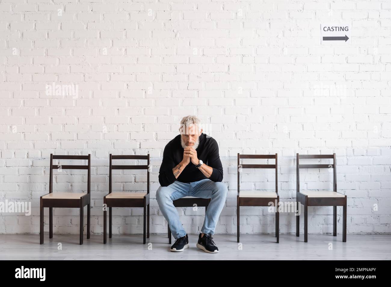 uomo premuroso in attesa di casting in teatro. Traduzione del tatuaggio: om, shanti, pace. Dovete scavare i pozzi profondi se desiderate ottenere acqua pulita Foto Stock