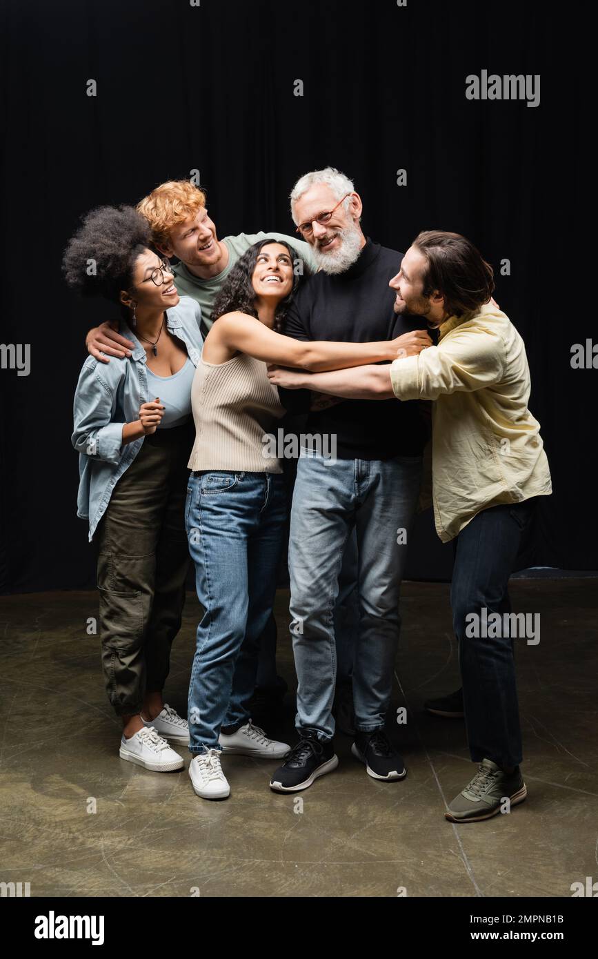 felici studenti multiculturali che abbraccia insegnante di capacità recitative nella scuola di teatro Foto Stock