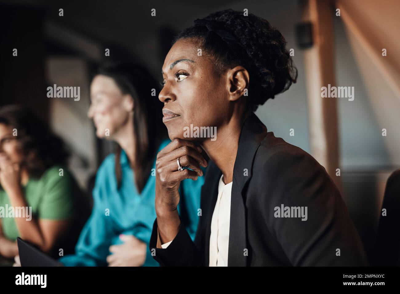 Donna d'affari premurosa con mano sul mento durante la riunione in ufficio Foto Stock
