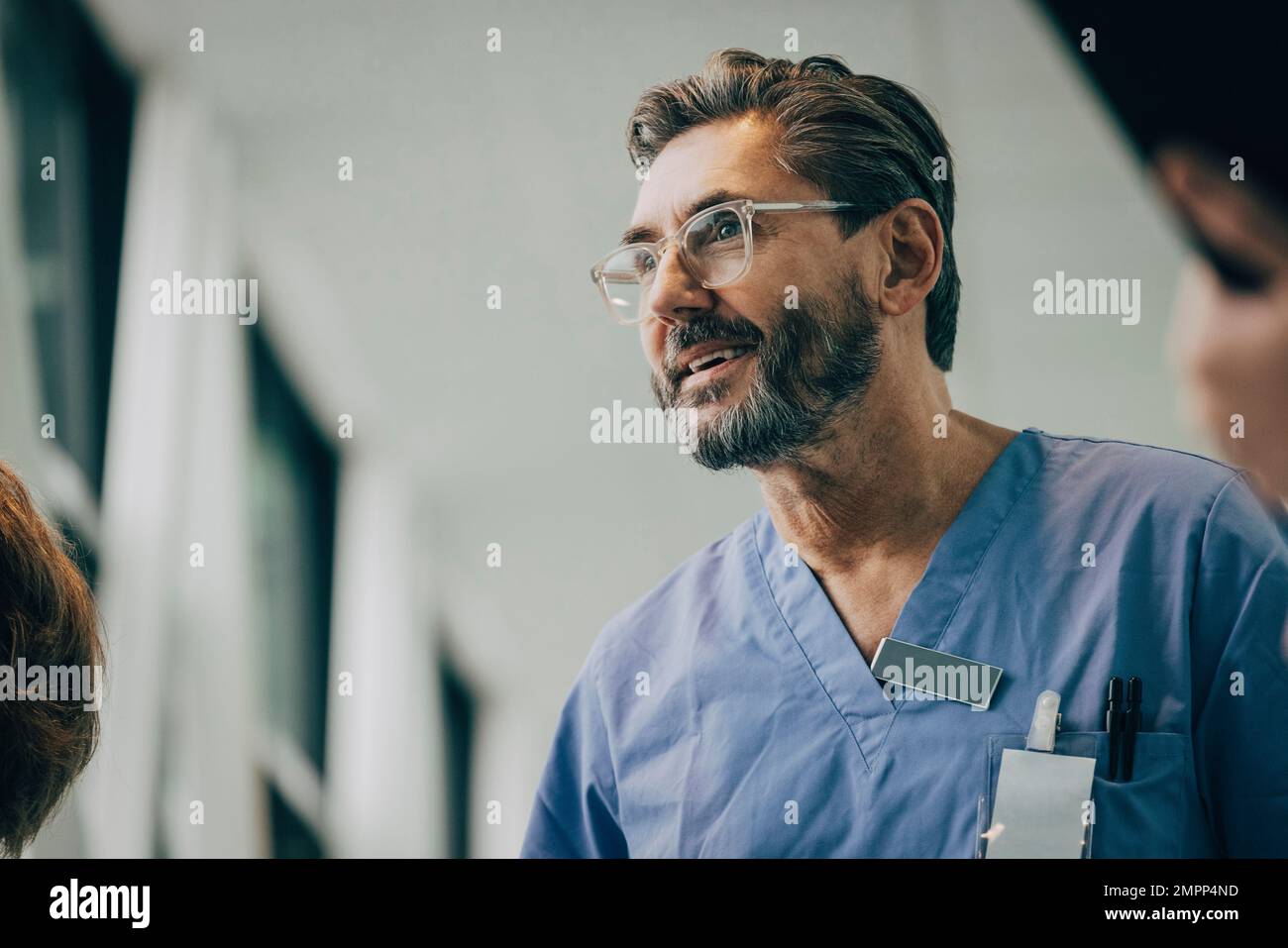 Vista dal basso angolo di un medico maschile sorridente e maturo che indossa occhiali in ospedale Foto Stock