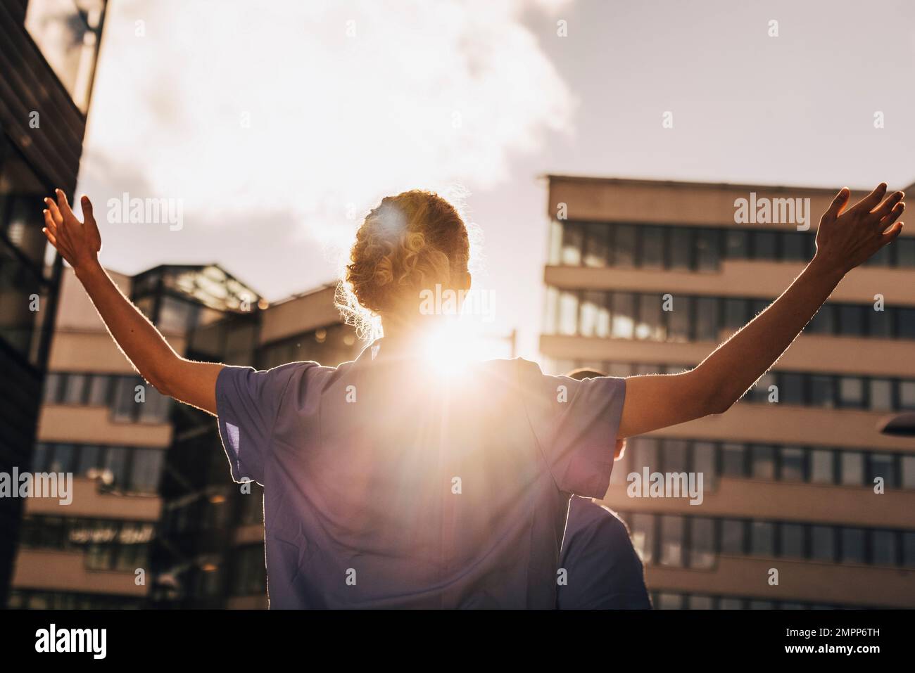 Vista dall'angolo basso dell'infermiera con le braccia distese in piedi e rivolte verso la luce solare Foto Stock