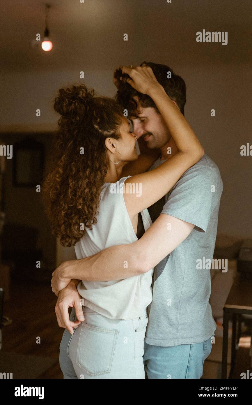 Ragazza che sfrega il naso con il ragazzo in piedi a casa Foto Stock