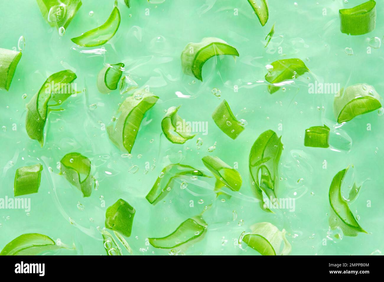 Sfondo di gel di aloe con fette di aloe. Tagliare le fette di aloe in gel di aloe cosmetico trasparente. Giacitura piatta. Vista dall'alto. Foto Stock