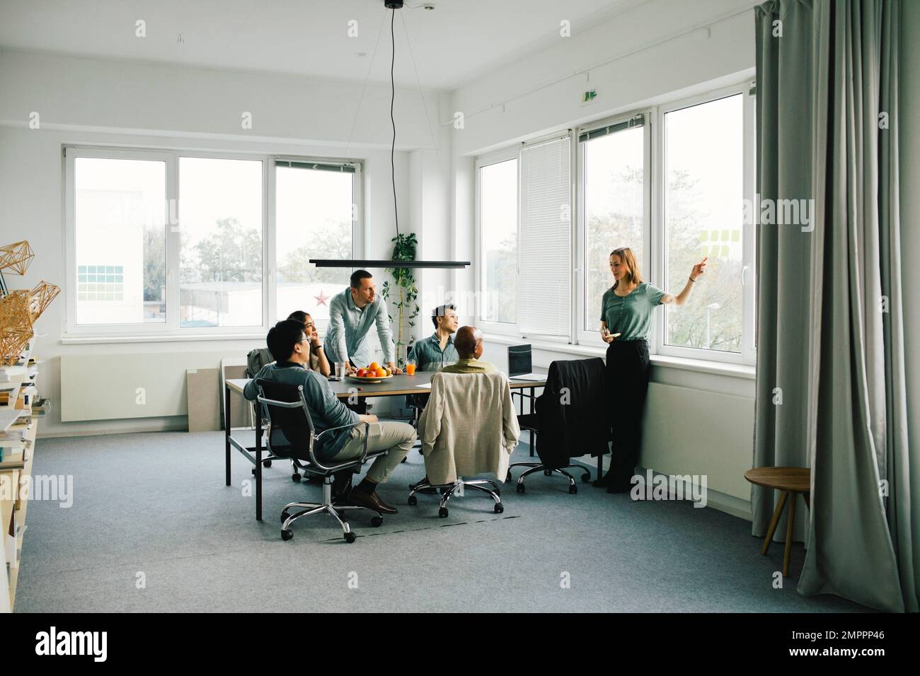 Donna d'affari che discute con i colleghi durante la sessione di brainstorming in ufficio Foto Stock