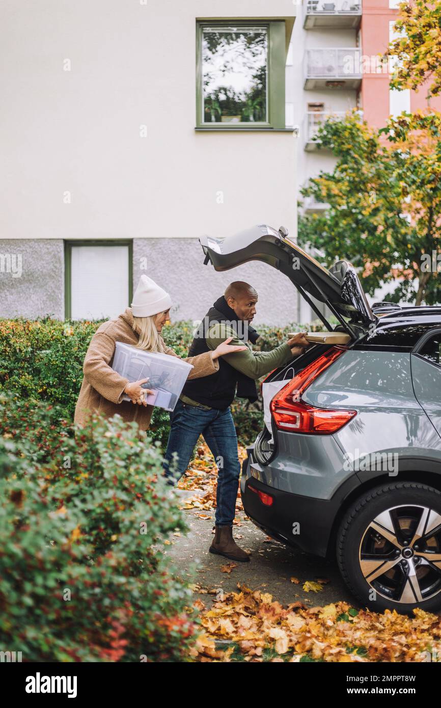 Donna matura che assiste l'uomo durante il caricamento del bagagliaio dell'automobile durante il trasferimento della casa Foto Stock