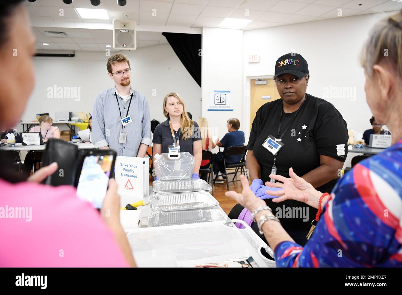Cape Coral, FL, USA--11/13/22--Renee' S. Anderson, responsabile delle collezioni del National Museum of African American History and Culture (cappello nero) discute su come salvare i tesori danneggiati dalla tempesta in un centro di recupero di disastro della FEMA-state istituito presso il centro di Lake Kennedy. La FEMA e lo Smithsonian Institution co-sponsorizzano la Heritage Emergency National Task Force, una partnership di 62 organizzazioni di servizio nazionali e agenzie federali. HENTF è stato creato per proteggere il patrimonio culturale dagli effetti dannosi delle catastrofi naturali e di altre emergenze. È unita da FEMA Environmental and Hist Foto Stock