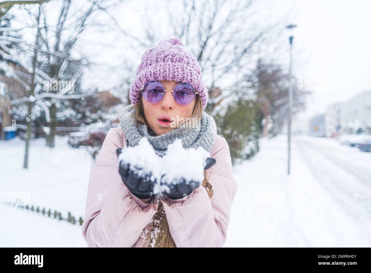 Una donna con occhiali da sole su neve soffiata nelle sue mani