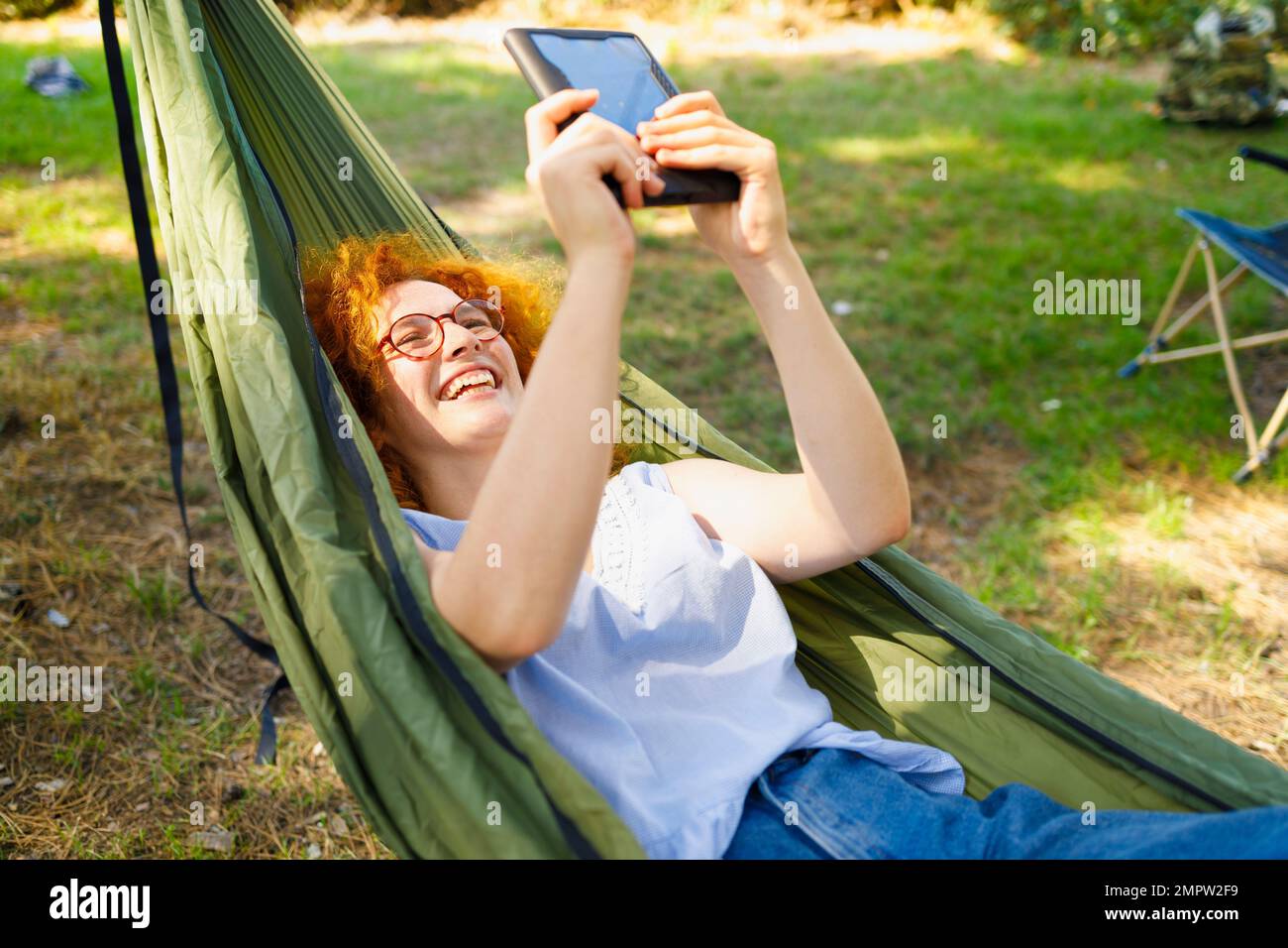 Una donna che riposa e legge in un'amaca in un giorno di primavera Foto Stock