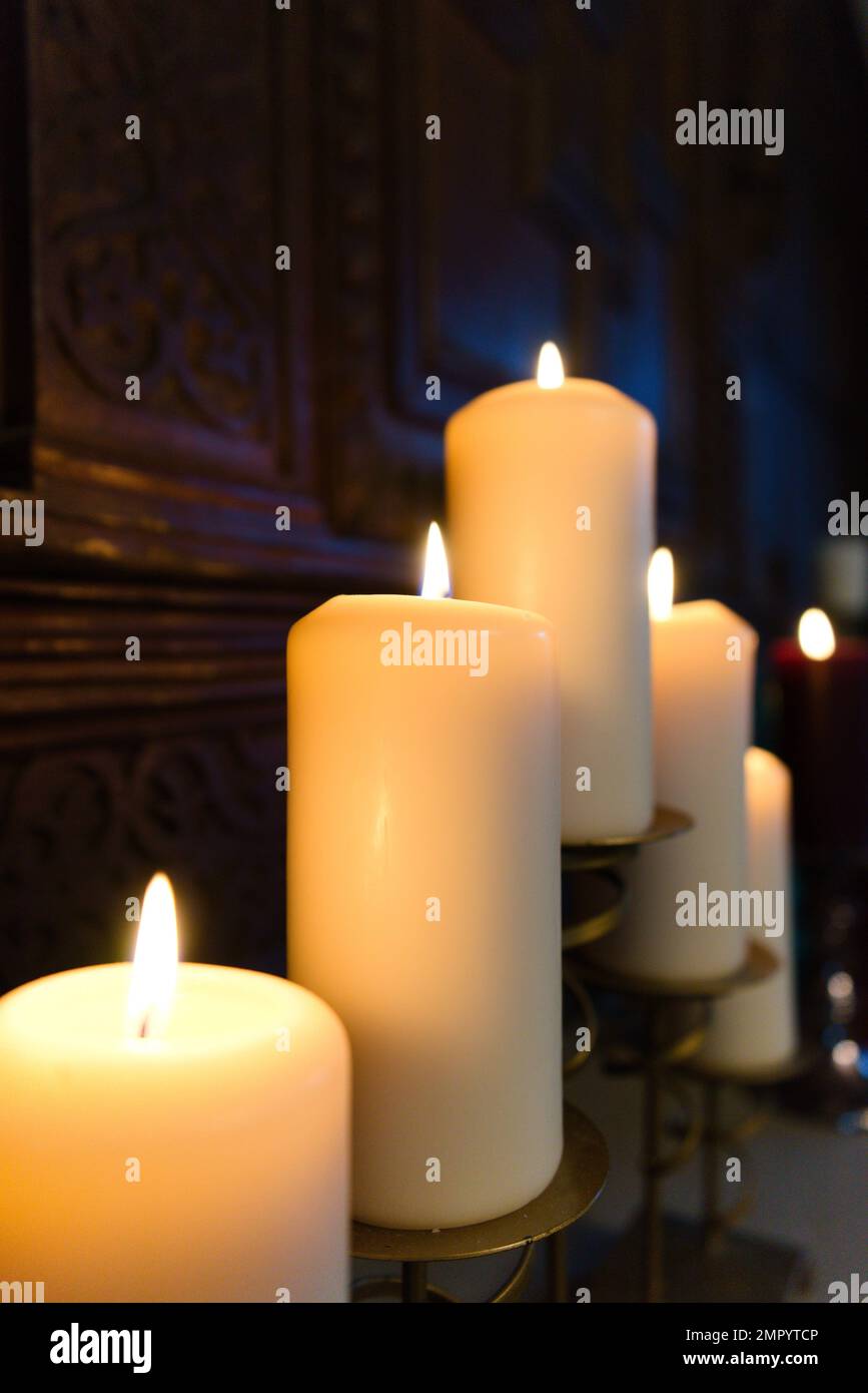 Cinque grandi candele bianche di Natale brucianti sulla parte superiore del  fuoco posto davanti ai pannelli di quercia di legno con una candela rossa  solita nel backgroun Foto stock - Alamy
