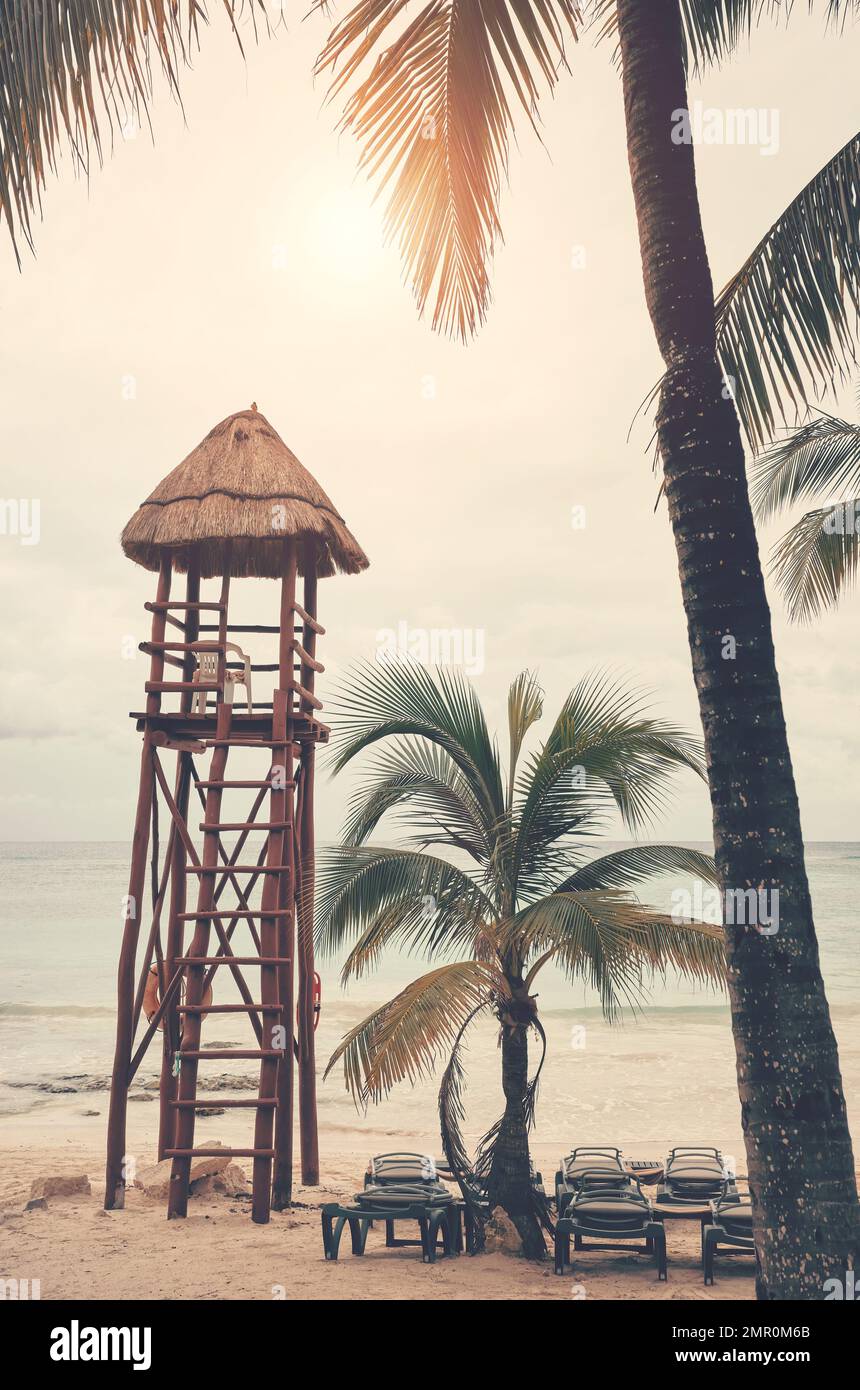 Immagine dai toni retrò di una spiaggia tropicale vuota con torre del bagnino, concetto di viaggio. Foto Stock