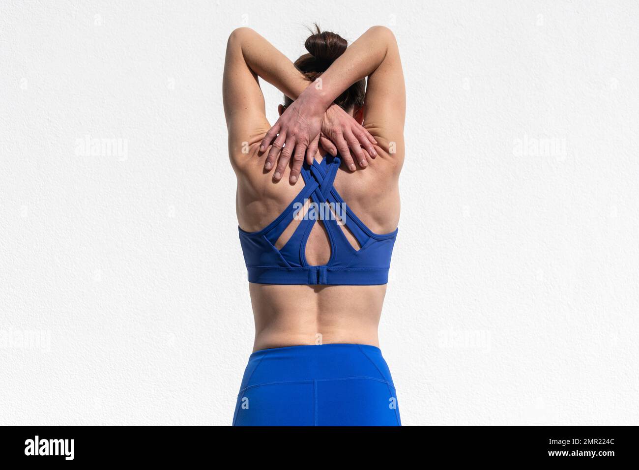 Vista posteriore di una donna sportiva che fa un braccio e una spalla stretch, warm up concetto di esercizio. Foto Stock