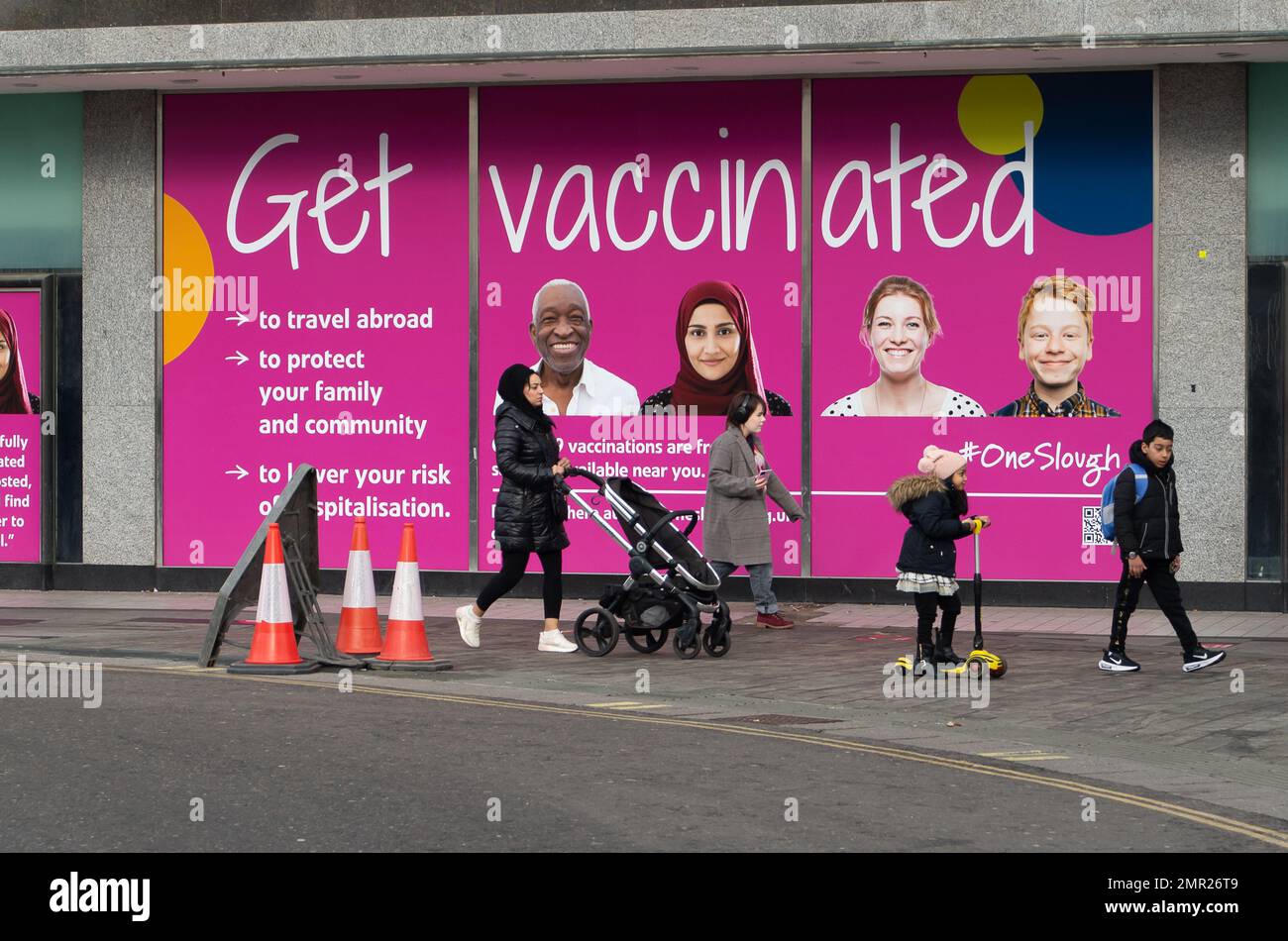 Slough, Berkshire, Regno Unito. 31st gennaio 2023. Gli acquirenti passano oltre un cartello Get vaccinated in Slough. Il comitato misto per la vaccinazione e l'immunizzazione (JCVI) ha affermato che le persone a più alto rischio di grave Covid dovrebbero ricevere un richiamo di Covid-19 nell'autunno 2023. Le persone anziane e immunosoppresse, dovrebbero avere un richiamo supplementare in primavera. Credit: Maureen McLean/Alamy Live News Foto Stock