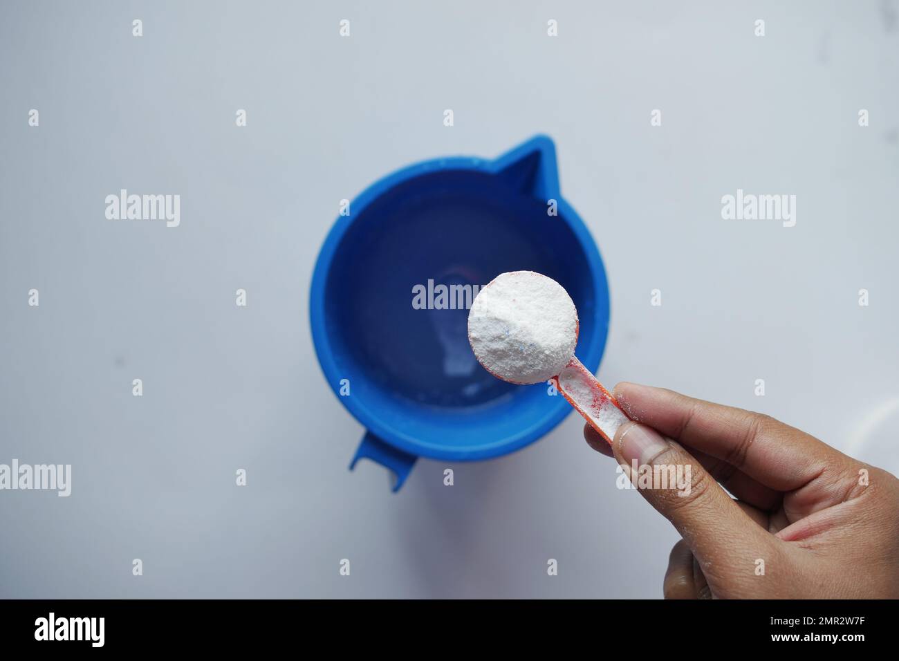 Polvere di lavaggio in cucchiaio di plastica su sfondo nero vista dall'alto. Foto Stock