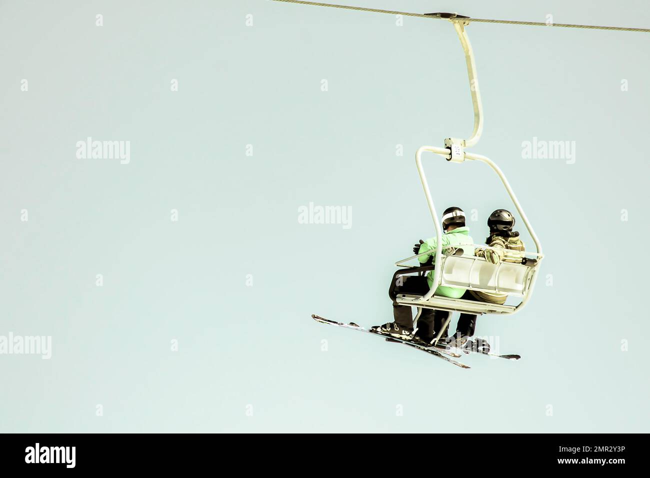 Scatto a basso angolo di uno skilift presso la stazione sciistica con due amici sciatori maschi a Gudauri in montagna in una giornata di sole inverno. Immagine cinematografica cielo blu. Es Foto Stock