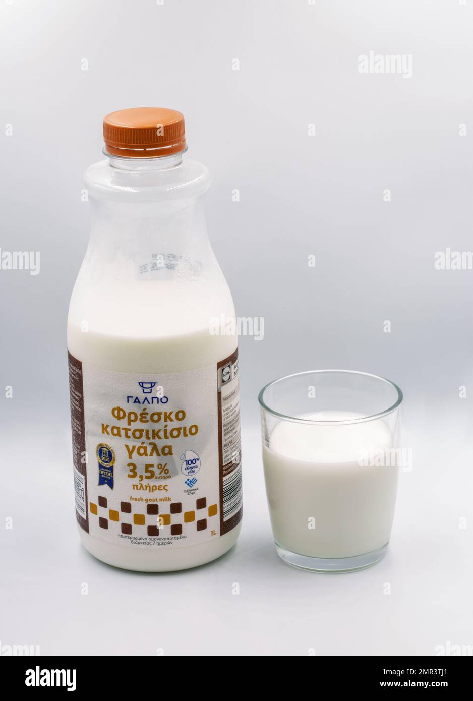 Corfù, Grecia - 05 agosto 2021: Sparo studio di bottiglia di latte di capra fresco greco e primo piano di vetro contro il bianco. Foto Stock
