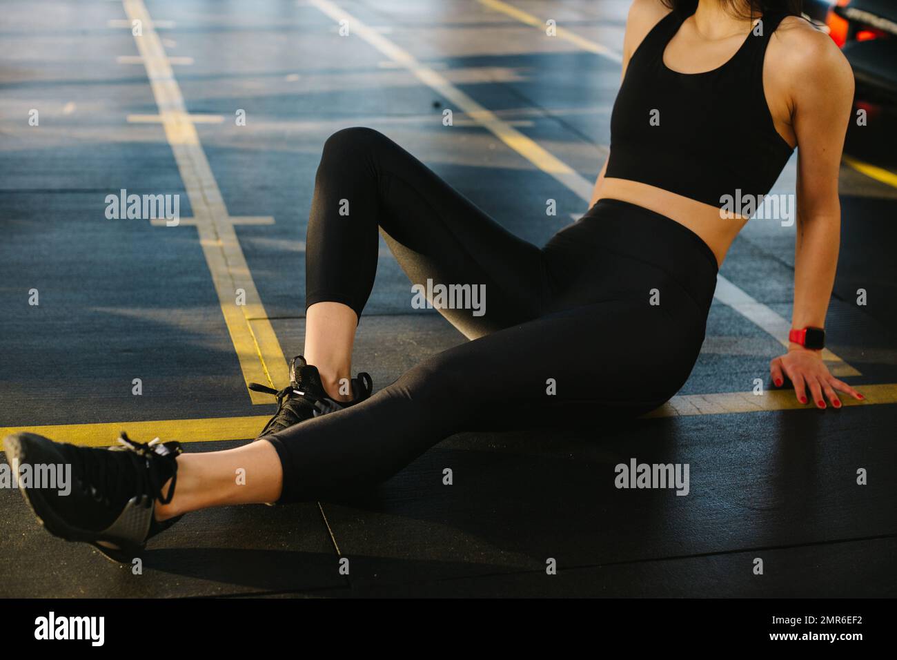 Primo piano, ragazza atletica in leggings neri seduta sul pavimento in  palestra. Riposando dopo l'esercitazione, i leggings bockup Foto stock -  Alamy