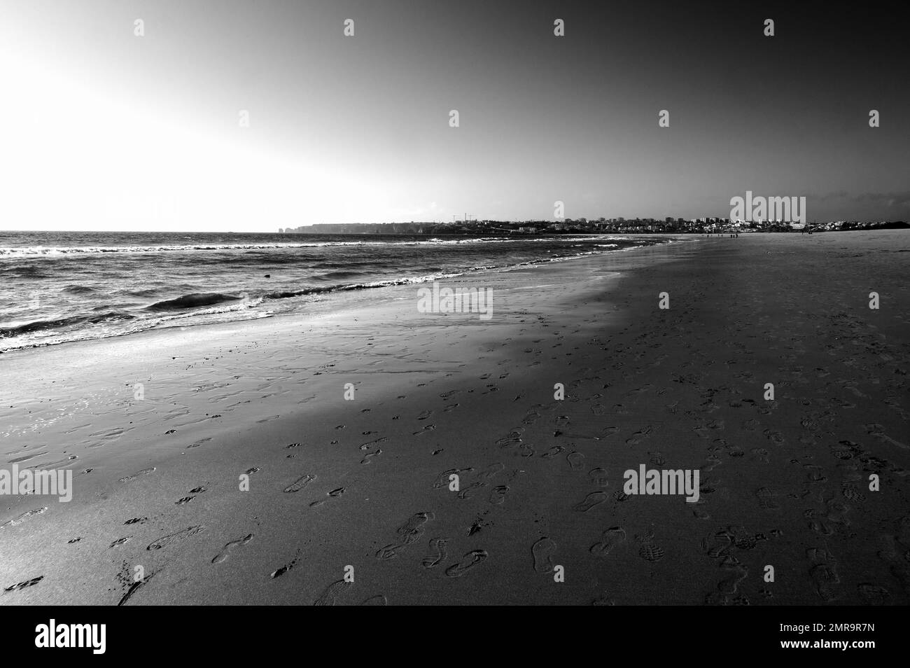 Una spiaggia di sabbia deserta e uno skyline della città in lontananza Foto Stock
