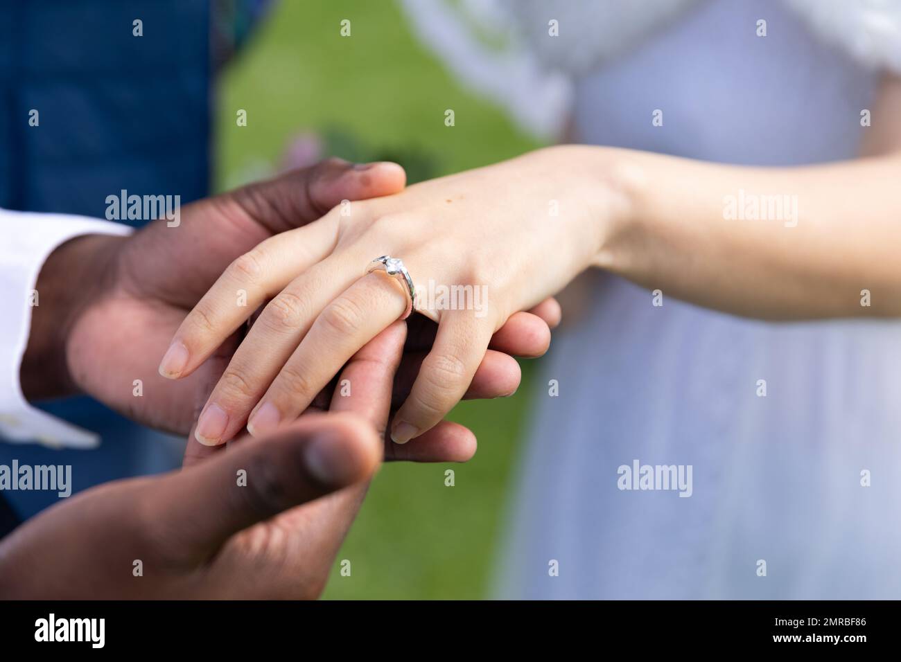 Mani di diverso sposo e sposa indossare anello di nozze all'aperto matrimonio, spazio copia Foto Stock