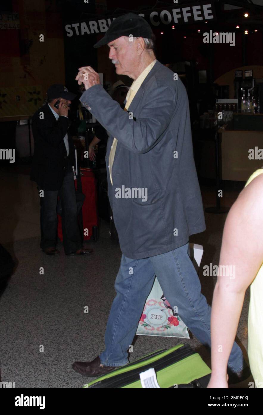 ESCLUSIVO!! Il leggendario attore, scrittore e comico britannico John Cleese, famoso per le apparizioni e la scrittura di serie televisive e film tra cui 'Monty Python's Flying Circus', 'Fawlty Towers, 'Shrek' e 'Will & Grace', arriva all'aeroporto internazionale di Miami per prendere un volo. Cleese si assicurò di portare fuori dai bagagli quello che sembrava essere un nuovo computer portatile Apple, riponendolo in una borsa a mano. Miami, Florida. 3/10/11. Foto Stock