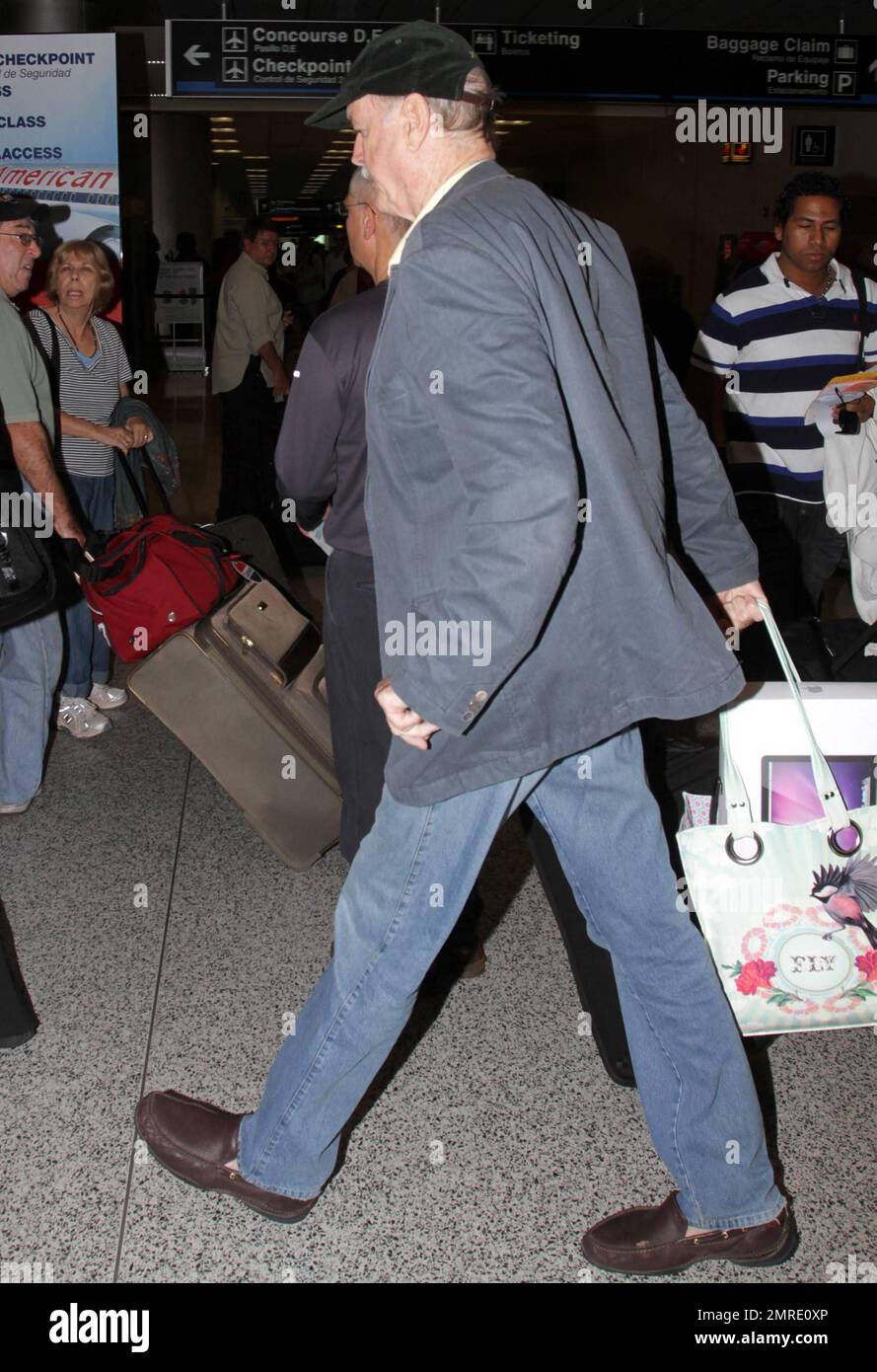 ESCLUSIVO!! Il leggendario attore, scrittore e comico britannico John Cleese, famoso per le apparizioni e la scrittura di serie televisive e film tra cui 'Monty Python's Flying Circus', 'Fawlty Towers, 'Shrek' e 'Will & Grace', arriva all'aeroporto internazionale di Miami per prendere un volo. Cleese si assicurò di portare fuori dai bagagli quello che sembrava essere un nuovo computer portatile Apple, riponendolo in una borsa a mano. Miami, Florida. 3/10/11. Foto Stock