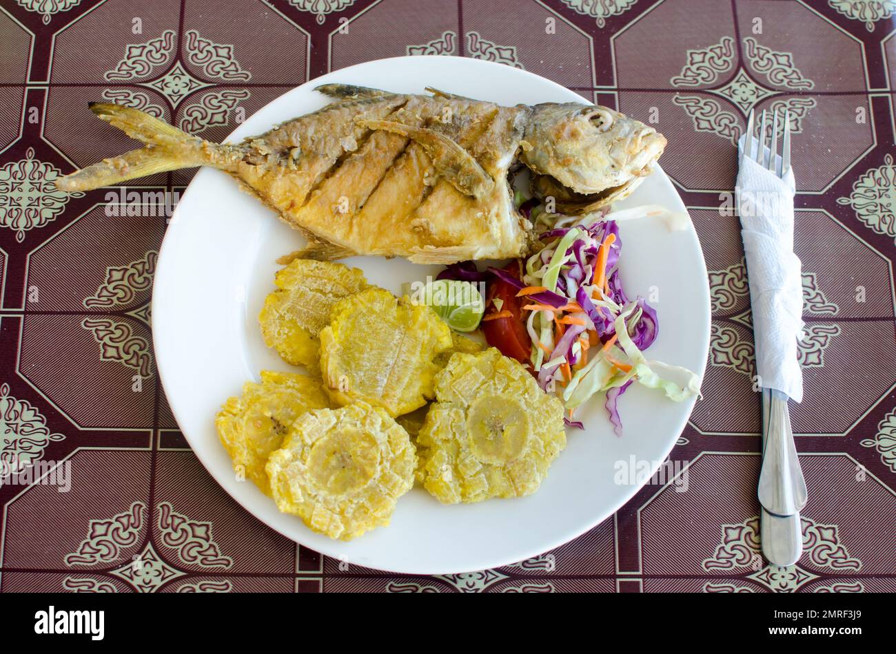 Pesce fritto intero con patacones, come è servito al turista nelle isole Guna Yala a Panama Foto Stock