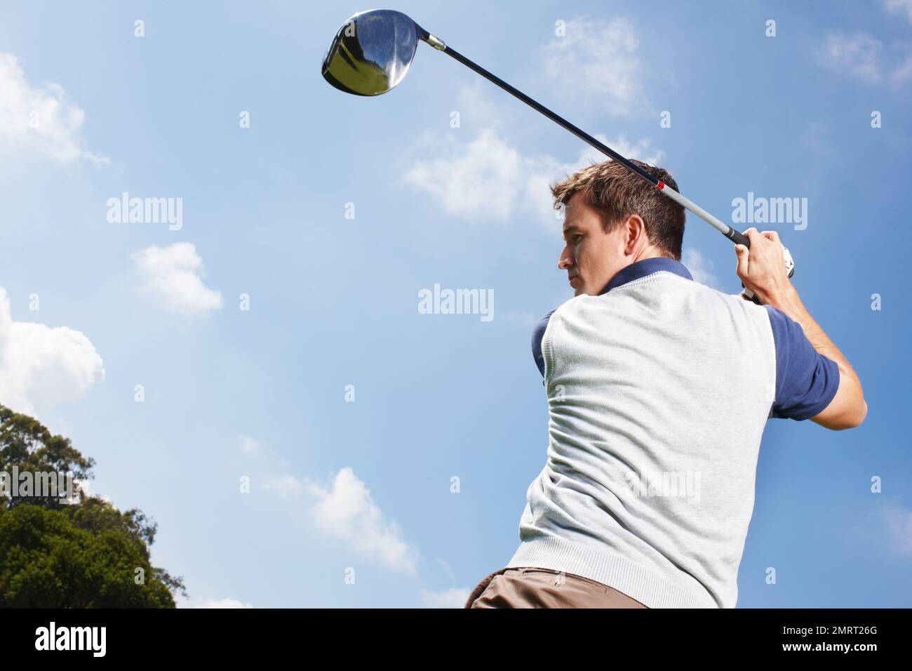 Che esperto di golf. Giovane uomo in piena oscillazione durante una partita di golf contro un cielo blu. Foto Stock