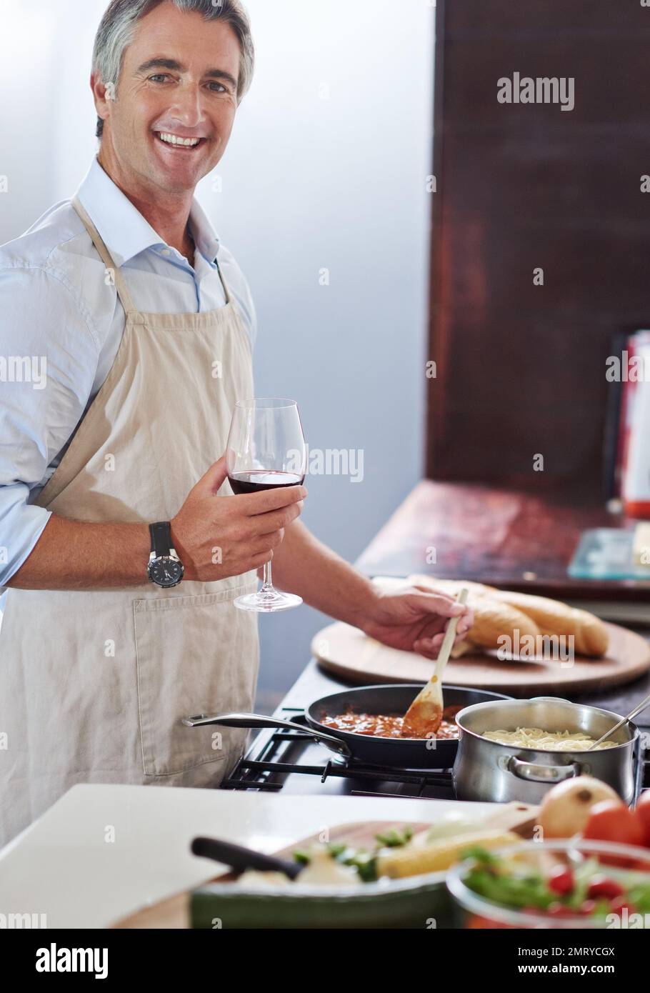 Penso che abbia bisogno di più vino. un uomo maturo che cucina in cucina. Foto Stock